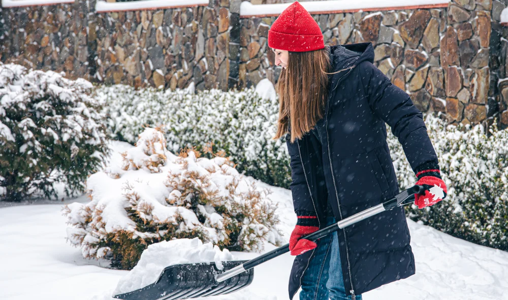 young woman cleans snow yard snowy weather Oakville, Ontario